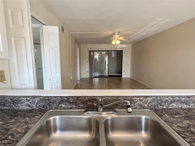 details with a textured ceiling, sink, ceiling fan, and dark tile flooring