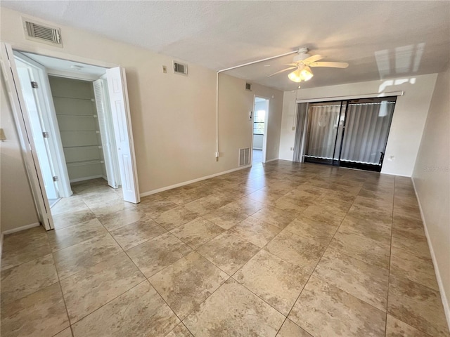 tiled spare room with ceiling fan and a textured ceiling