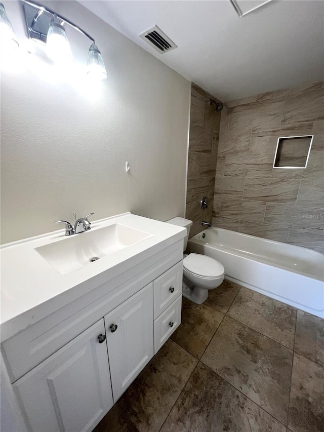 full bathroom featuring tiled shower / bath, toilet, tile floors, and vanity