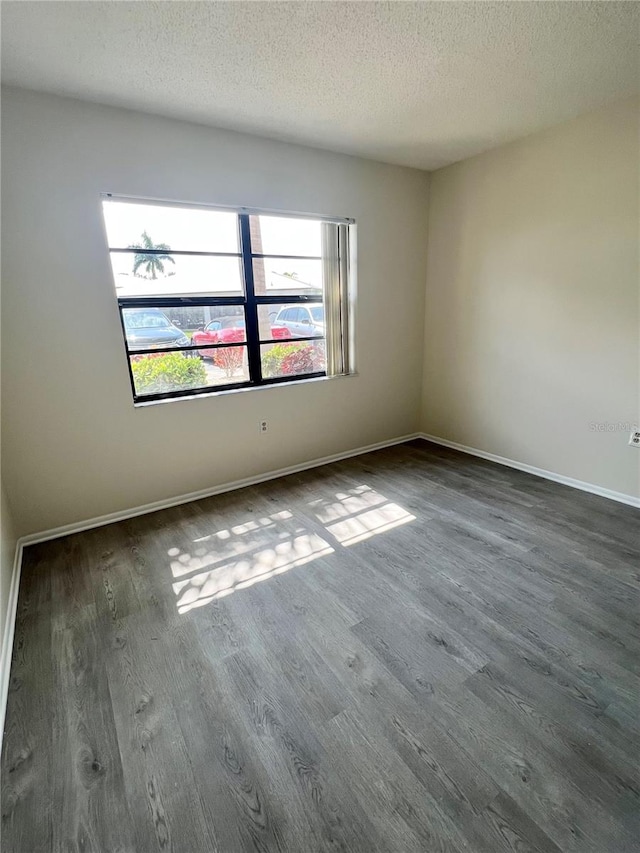 empty room with dark hardwood / wood-style flooring and a textured ceiling