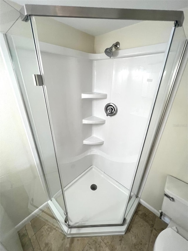 bathroom featuring walk in shower, toilet, and tile floors