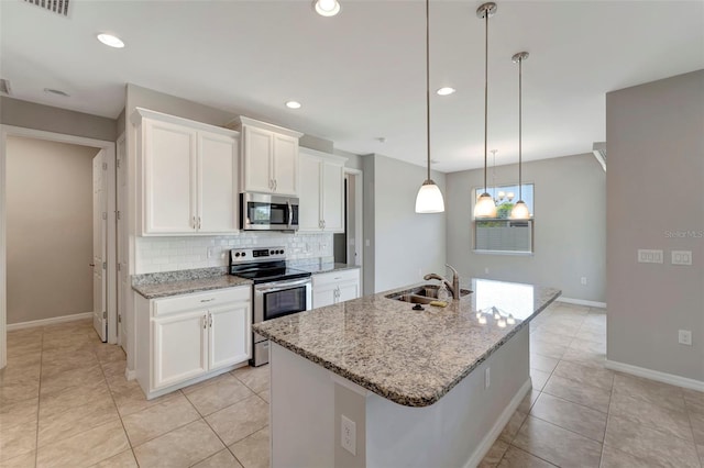 kitchen with stainless steel appliances, a kitchen island with sink, decorative light fixtures, backsplash, and sink