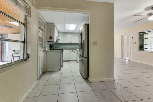 kitchen featuring range, light tile patterned floors, white cabinetry, and stainless steel refrigerator