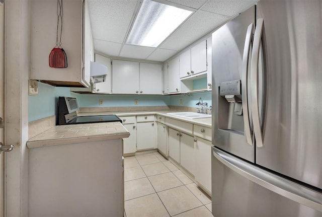 kitchen with white cabinetry, sink, stainless steel refrigerator with ice dispenser, a paneled ceiling, and range