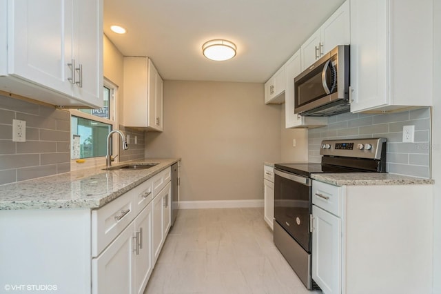 kitchen featuring white cabinetry, stainless steel appliances, light stone counters, sink, and tasteful backsplash