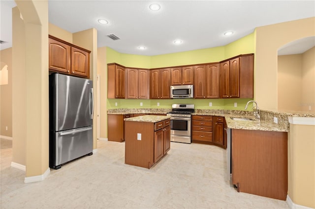 kitchen featuring stainless steel appliances, sink, a center island, and light tile floors