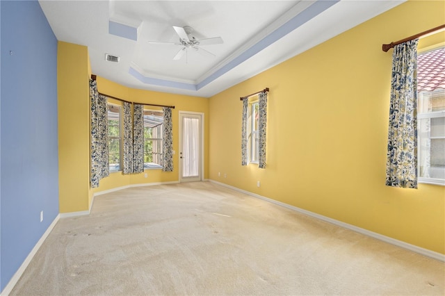 empty room with ceiling fan, a raised ceiling, and carpet floors