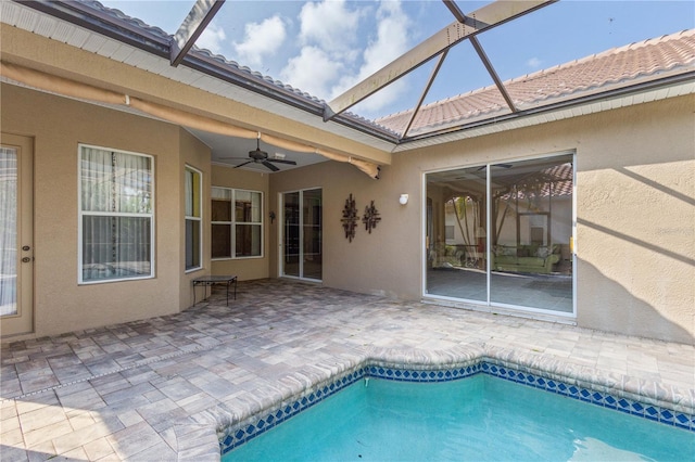 view of pool with a patio, glass enclosure, and ceiling fan