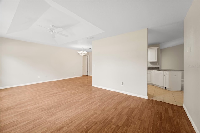 spare room featuring a tray ceiling, ceiling fan with notable chandelier, and light hardwood / wood-style flooring