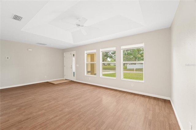 unfurnished room featuring a tray ceiling, light wood-type flooring, and ceiling fan