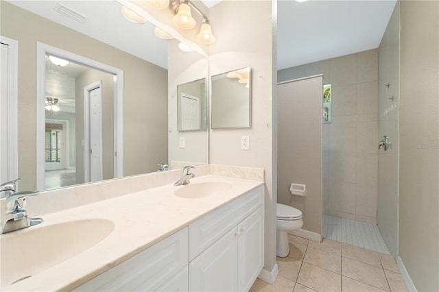 bathroom featuring dual sinks, tile flooring, vanity with extensive cabinet space, a healthy amount of sunlight, and toilet