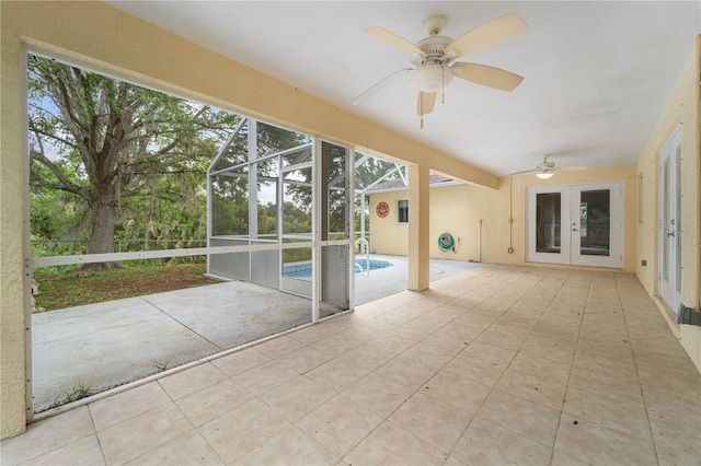 unfurnished sunroom featuring ceiling fan, french doors, and a wealth of natural light