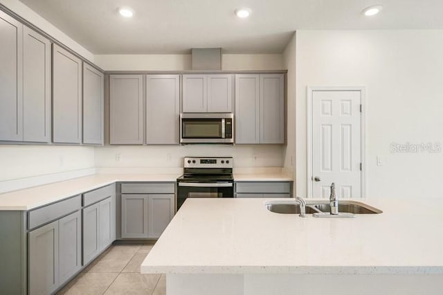 kitchen with sink, gray cabinets, light tile floors, and stainless steel appliances