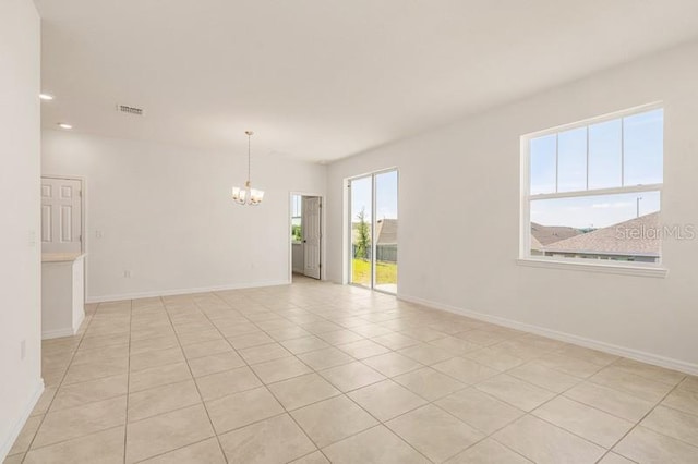 tiled empty room with an inviting chandelier