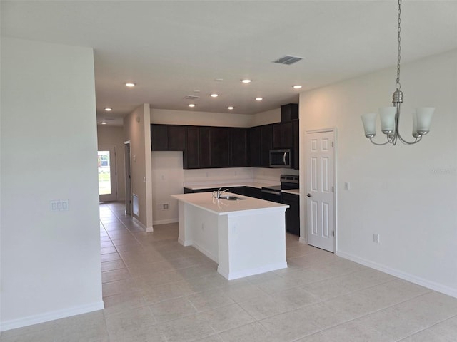 kitchen with hanging light fixtures, appliances with stainless steel finishes, a kitchen island with sink, sink, and light tile floors