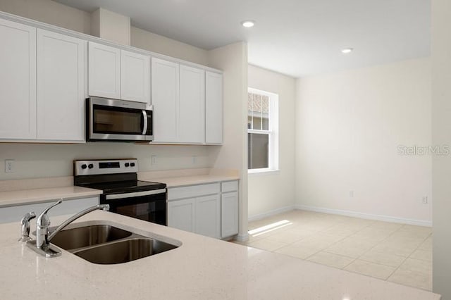 kitchen featuring sink, stainless steel appliances, light tile flooring, and white cabinetry