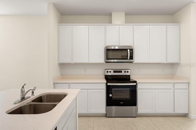 kitchen with stainless steel appliances, sink, white cabinetry, and light tile floors