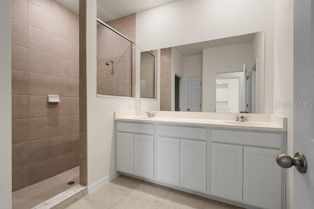 bathroom with tiled shower, tile floors, and dual vanity