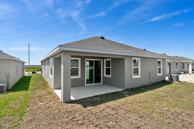 rear view of house featuring central AC, a lawn, and a patio area