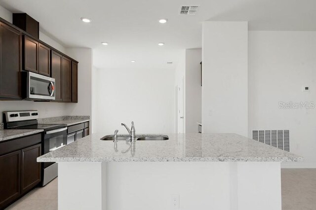 kitchen featuring sink, light stone countertops, dark brown cabinetry, and stainless steel appliances