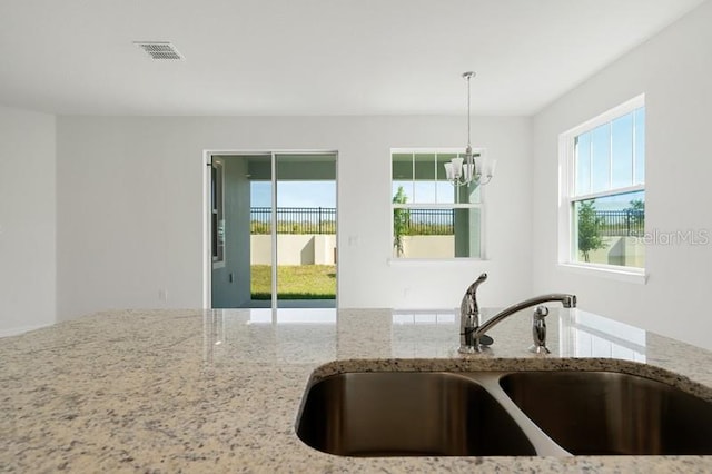 kitchen with a notable chandelier, sink, and light stone countertops