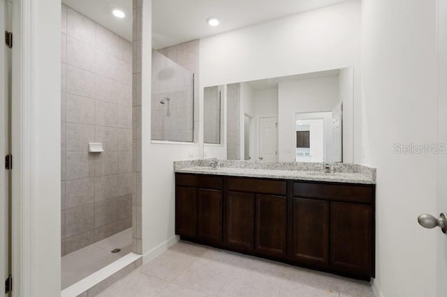 bathroom with tile floors, dual vanity, and a tile shower