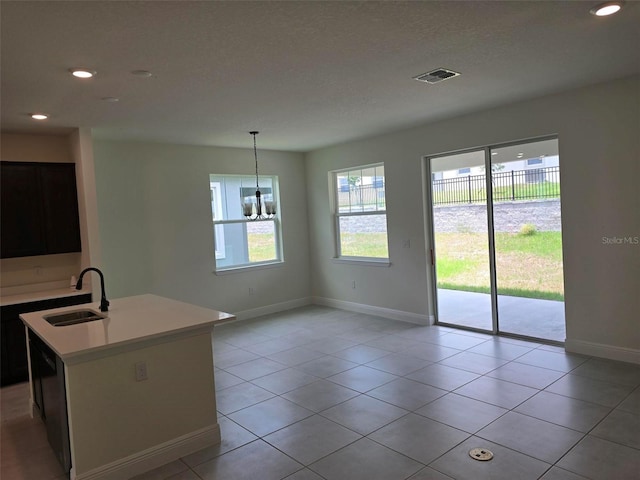 interior space featuring sink, an island with sink, light tile flooring, and pendant lighting