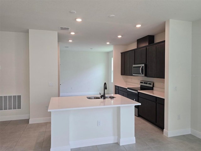 kitchen featuring stainless steel appliances, light tile flooring, a center island with sink, and sink