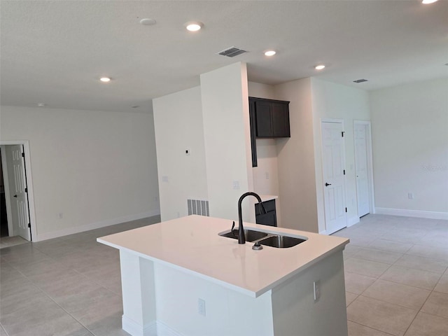 kitchen featuring sink, an island with sink, and light tile floors