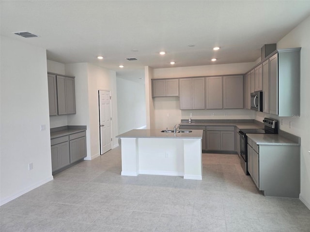 kitchen featuring gray cabinetry, a center island with sink, stainless steel appliances, sink, and light tile flooring