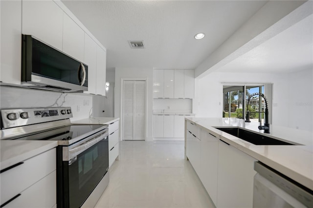 kitchen with white cabinetry, sink, light tile flooring, and stainless steel appliances