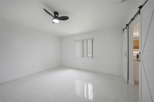 unfurnished bedroom featuring a barn door, ceiling fan, and multiple windows