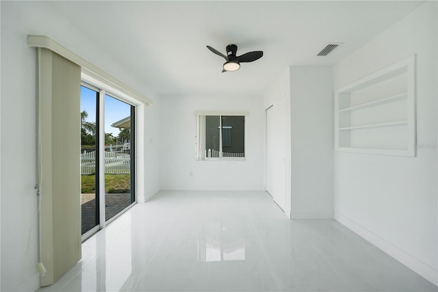 spare room featuring built in shelves, ceiling fan, and light tile flooring