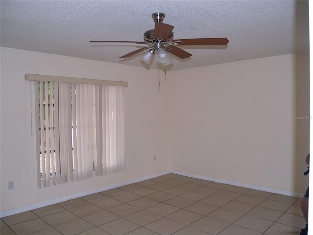 tiled empty room with ceiling fan and a textured ceiling