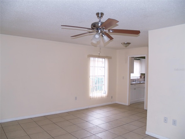 empty room featuring sink, a textured ceiling, ceiling fan, and light tile floors