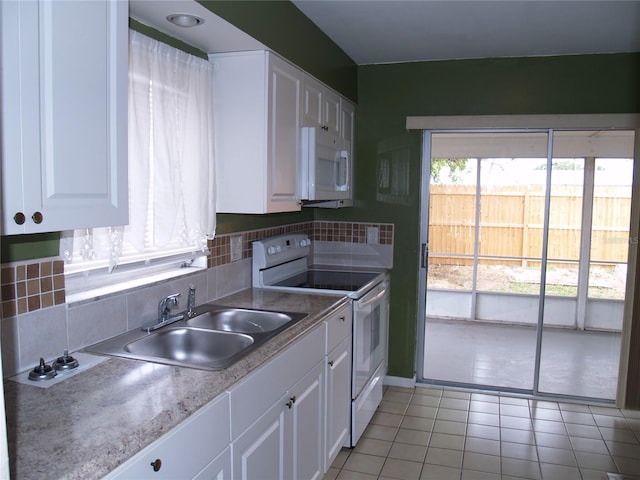 kitchen featuring white cabinets, light tile flooring, white appliances, and backsplash