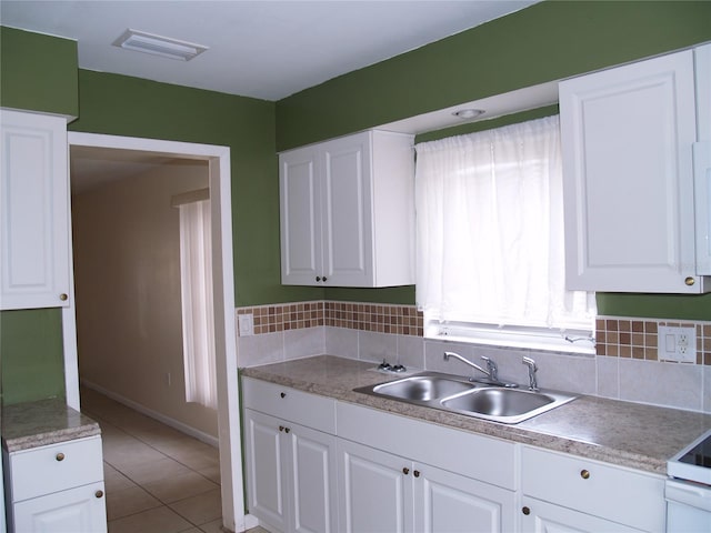 kitchen with backsplash, sink, white cabinetry, and light tile flooring