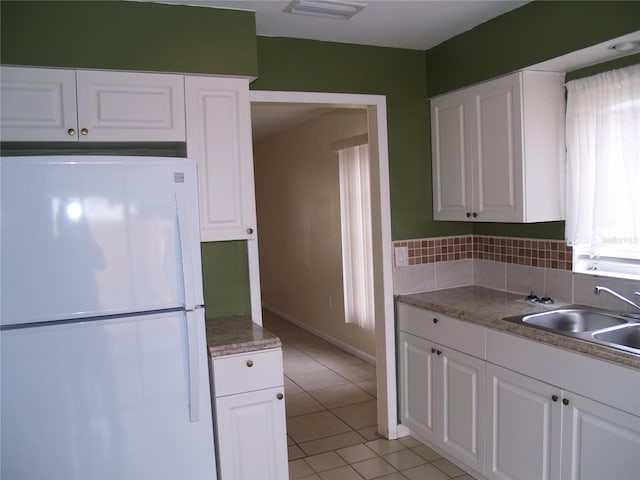 kitchen featuring white refrigerator, sink, white cabinetry, and light tile floors