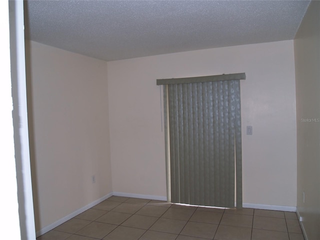 tiled empty room with a textured ceiling