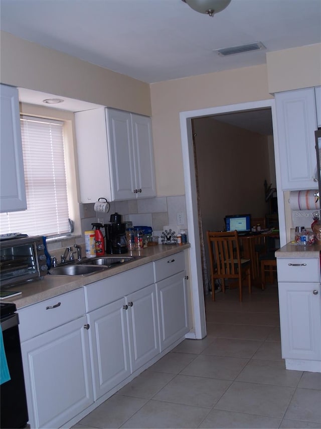 kitchen featuring sink, white cabinets, tasteful backsplash, and light tile floors