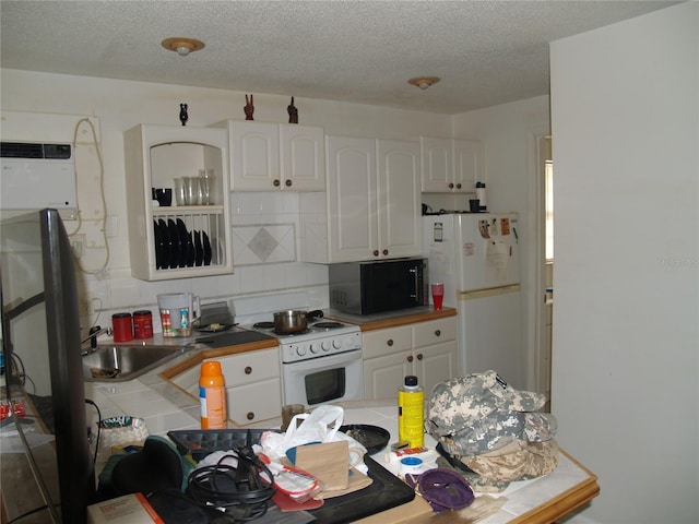 kitchen featuring tasteful backsplash, white appliances, tile counters, sink, and white cabinets