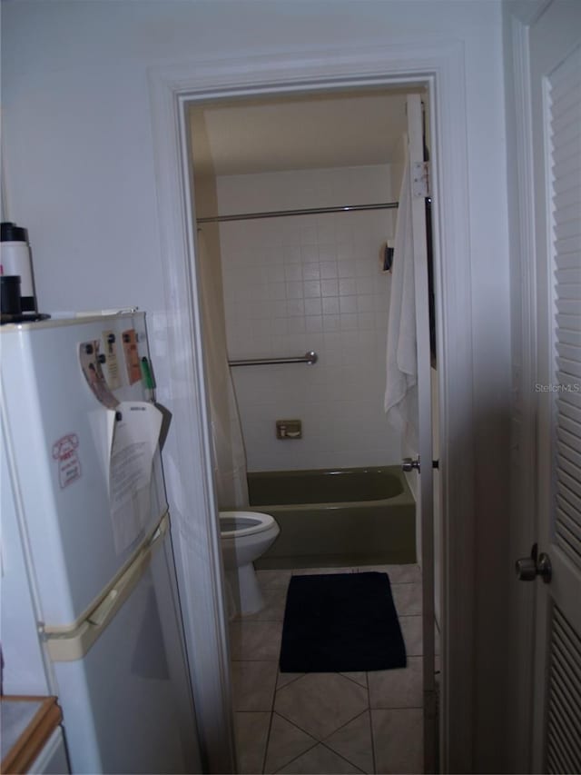 bathroom featuring tile floors, tiled shower / bath, and toilet