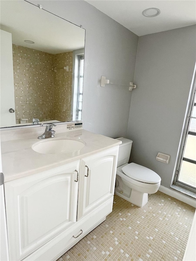 bathroom featuring a healthy amount of sunlight, vanity with extensive cabinet space, tile flooring, and toilet