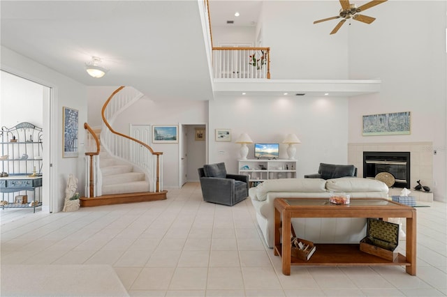 living room featuring ceiling fan, light tile patterned floors, a towering ceiling, and a fireplace