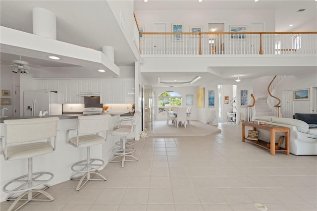 interior space featuring light tile patterned flooring, a high ceiling, and ceiling fan