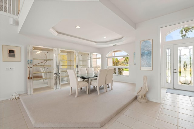 dining room featuring a raised ceiling and light carpet