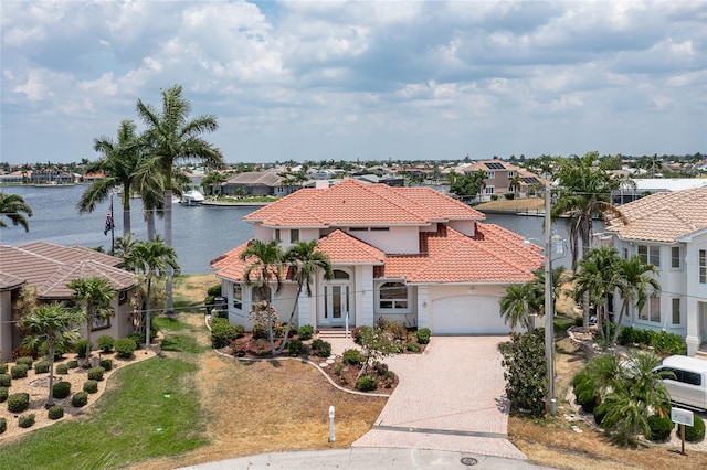 mediterranean / spanish-style home with a garage, a water view, and a front yard