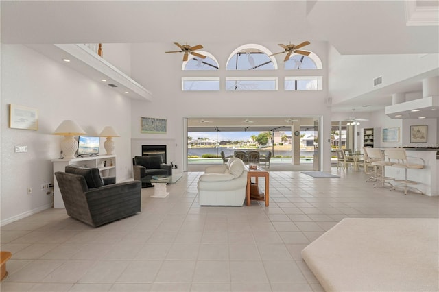 living room featuring ceiling fan, a high ceiling, and light tile patterned floors