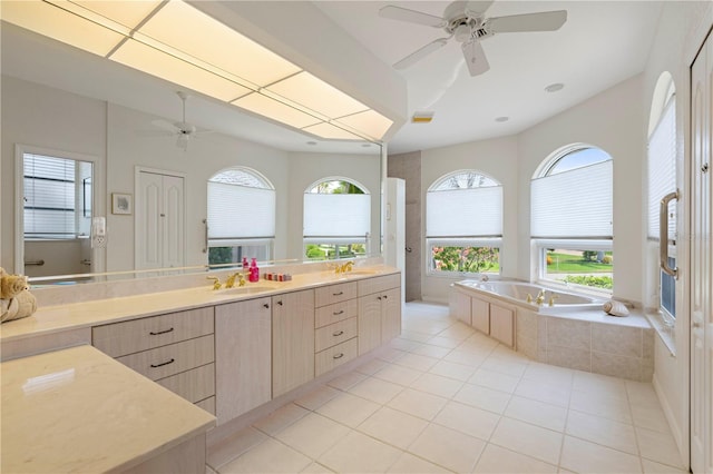 bathroom with tiled bath, vanity, ceiling fan, and tile patterned flooring