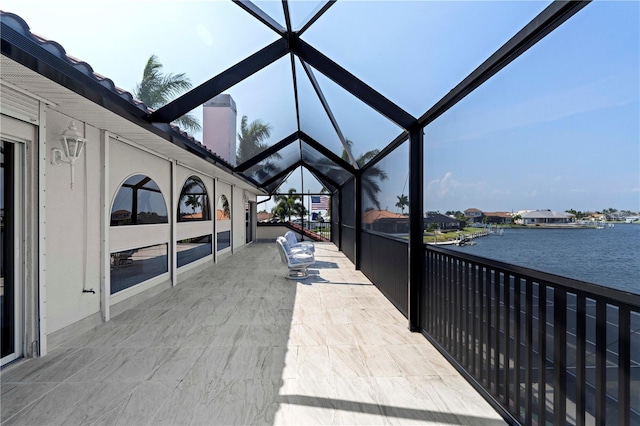 view of patio featuring glass enclosure and a water view